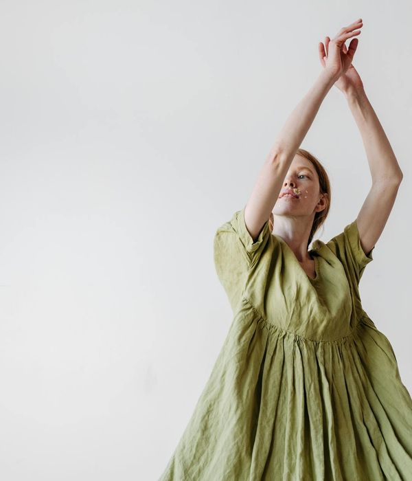 Woman in a calm, flowing movement pose in a serene studio.